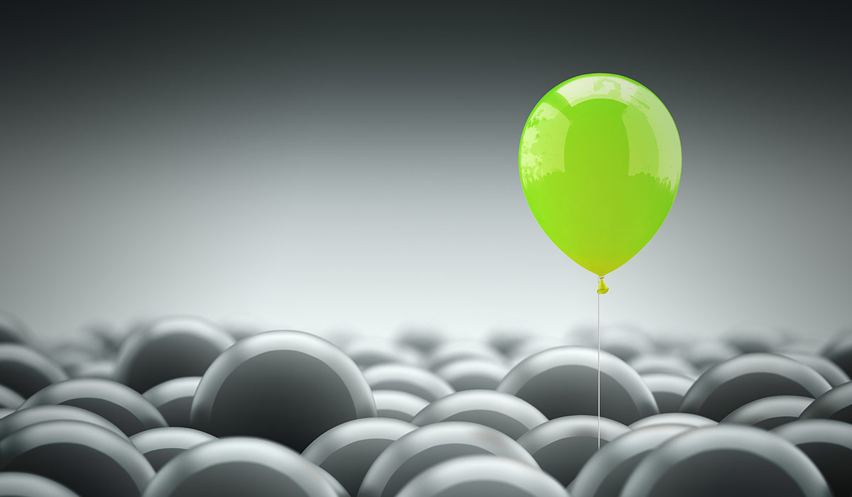 A group of grey balloons, with a single green ballon escaping. Image credit: iStock