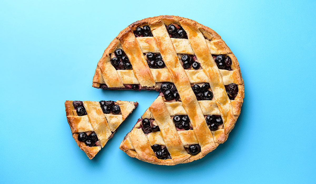 A blueberry pie with a slice cut out of it, against a bright blue backdrop. Image credit: Adobe Stock