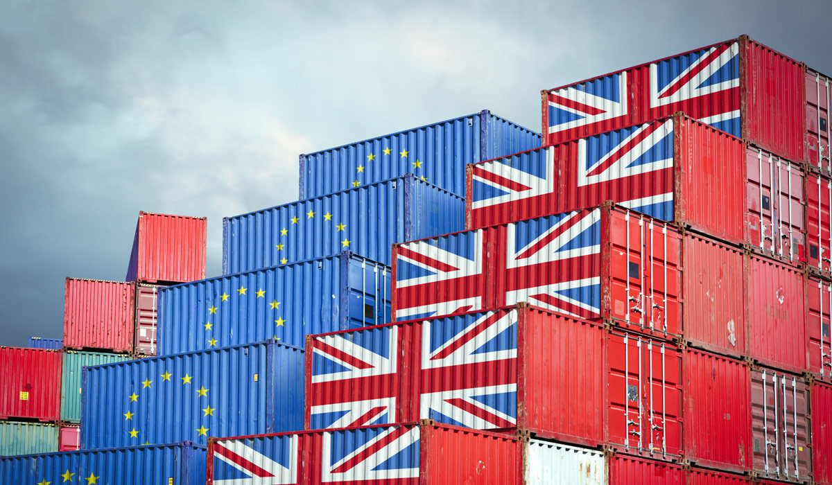 A stack of shipping containers, some with the Union Jack flag on them and some with the European flag on them. Image credit: iStock