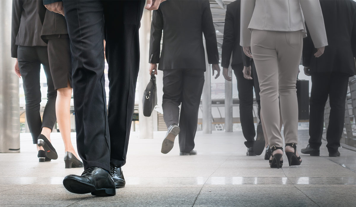 Businessman legs walking forward surrounded by other legs walking in an opposite direction. Image credit: Shutterstock